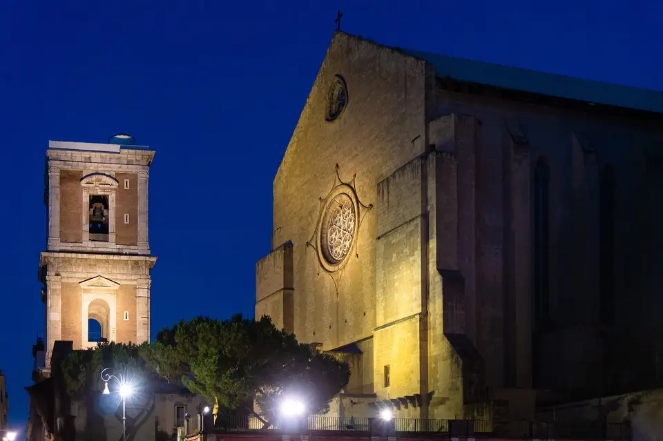 The façade and bell tower of the Basilica of Santa Chiara in Naples, in the evening.